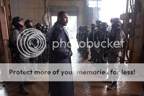 Stacker in a dapper long overcoat, standing in front of two lines of soldiers